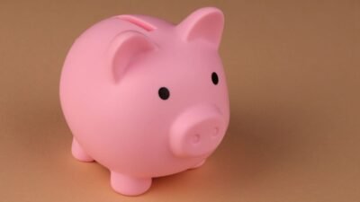 Alcancía rosa en forma de cerdito sobre un fondo café